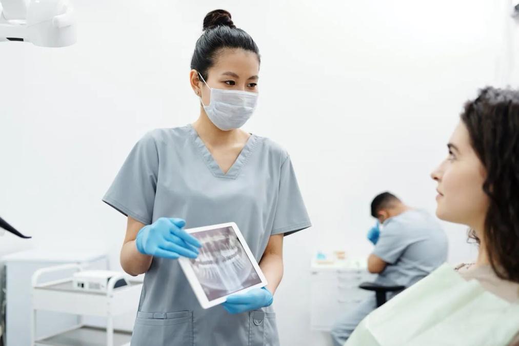 a female dentist is looking at an x-ray of a patient 's teeth on a tablet .