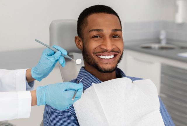 a man is sitting in a dental chair while a dentist examines his teeth .