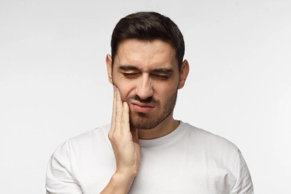 a man is holding his face in pain because of a toothache .