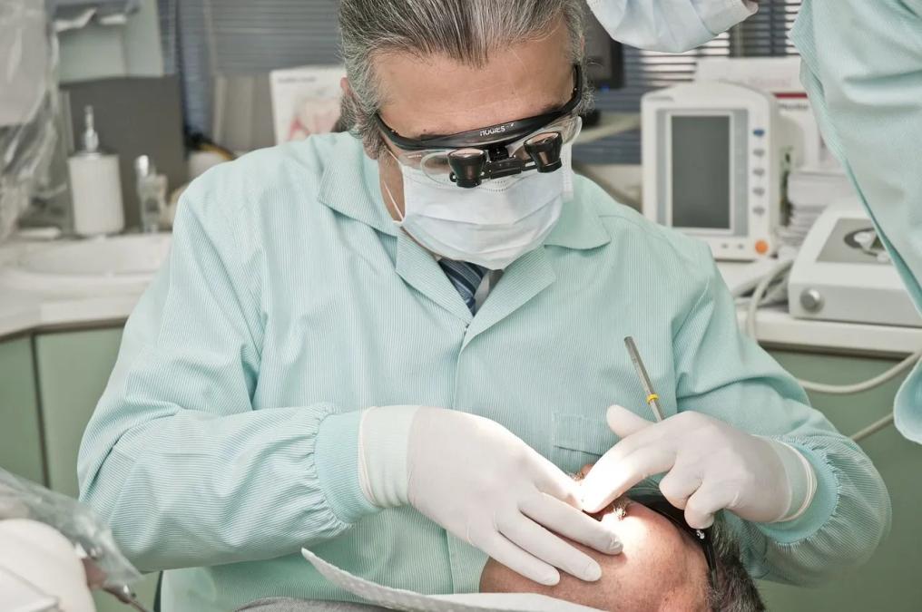 a dentist is examining a patient 's teeth in a dental office .