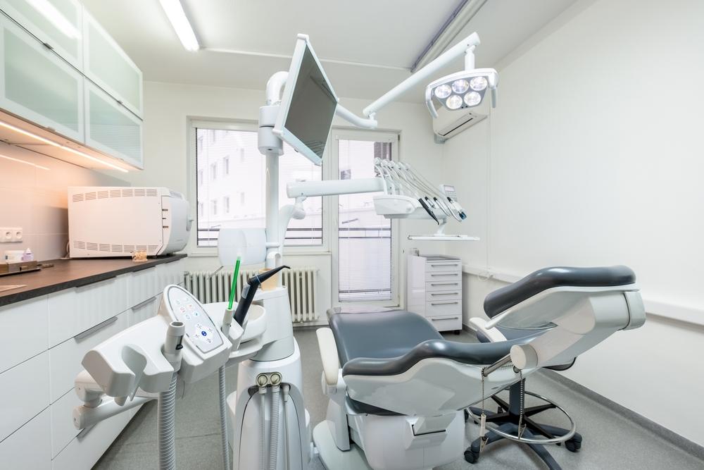 A modern dental office with a gray dental chair and equipment.