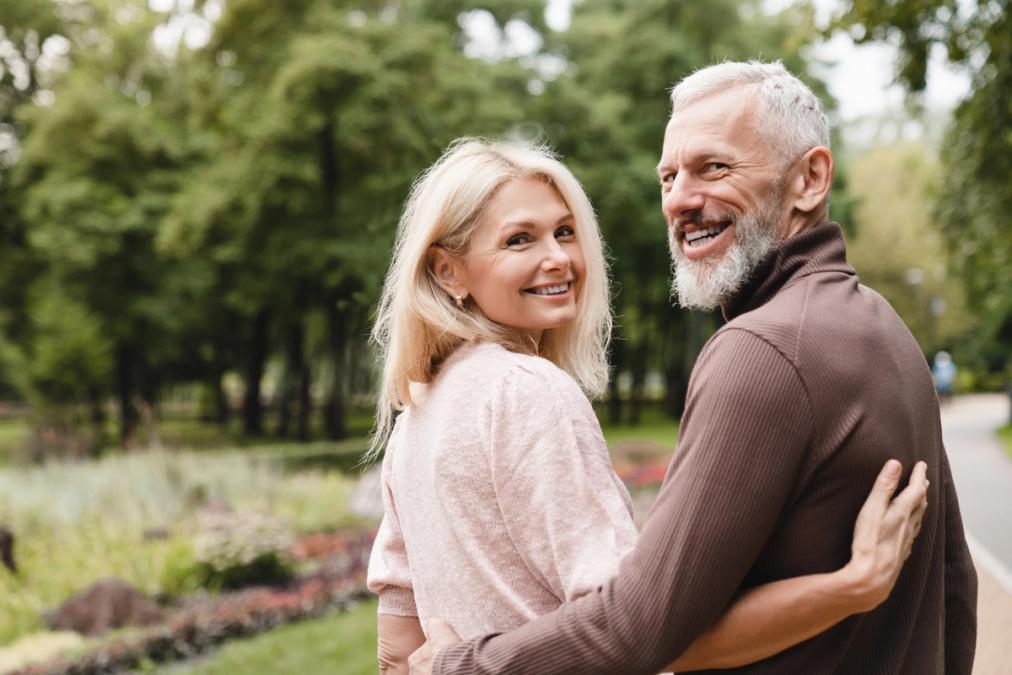 a man and a woman are hugging each other in a park .