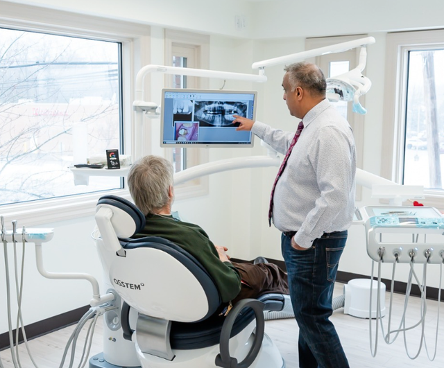 a man sitting in a dental chair looking at an x-ray