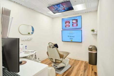 a dental office with a dental chair and a television on the wall .