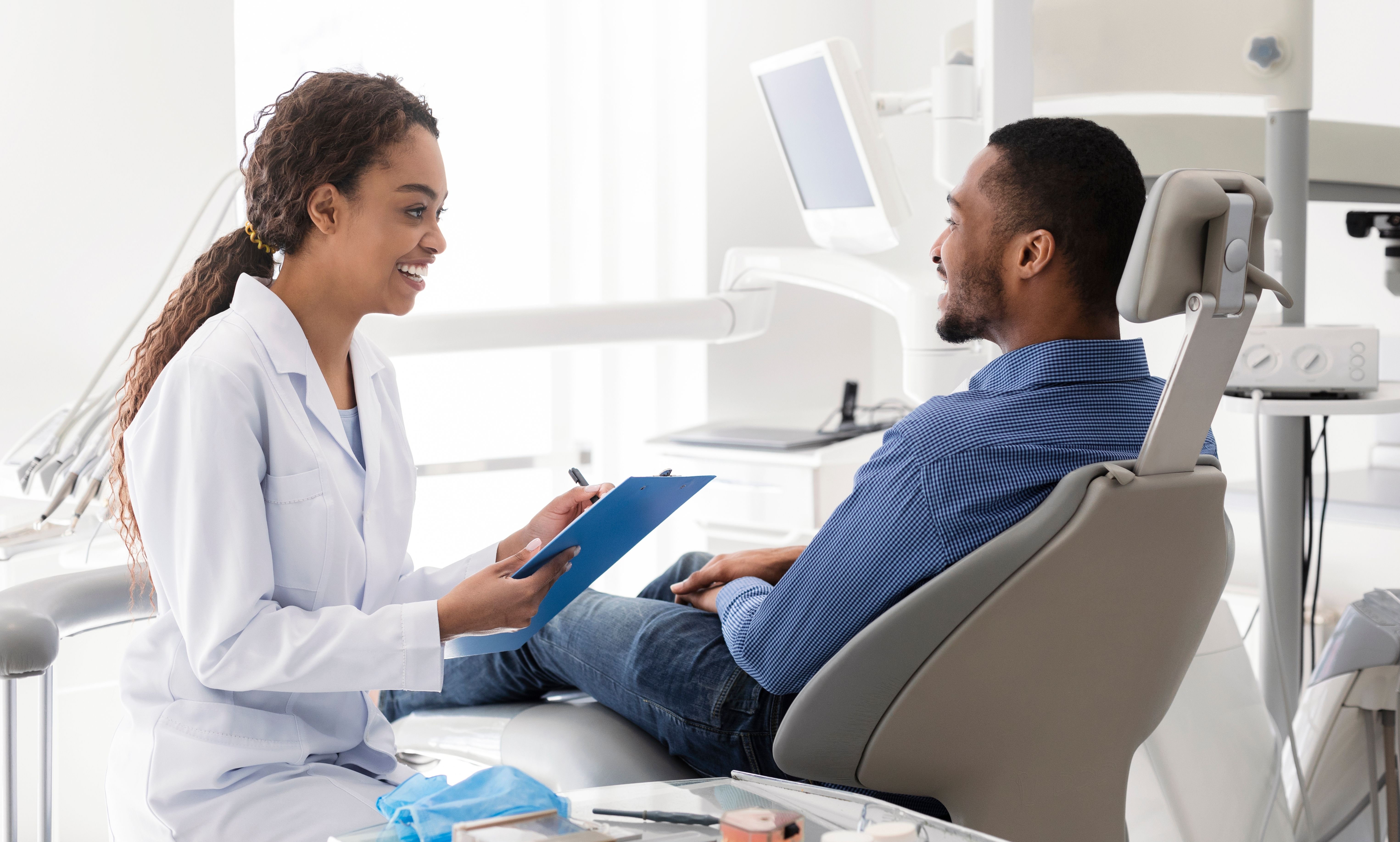 a dentist is talking to a patient in a dental chair .
