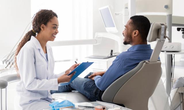 a dentist is talking to a patient in a dental chair .