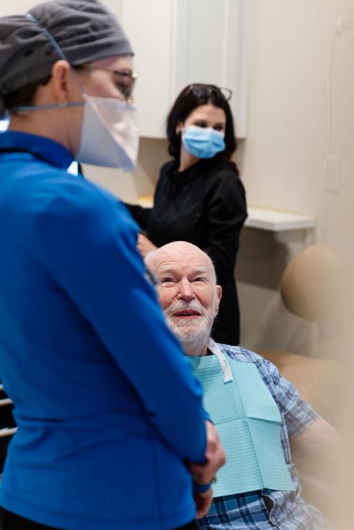 a man in a dental chair talking to a nurse