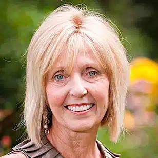 a woman with blonde hair and blue eyes is smiling for the camera .