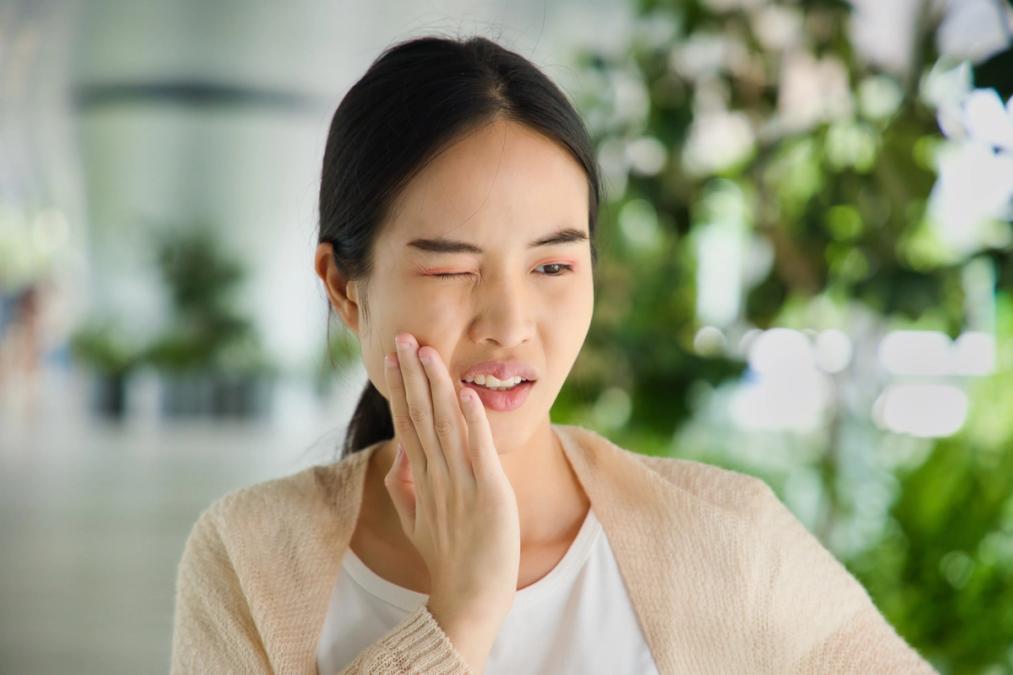 a woman is holding her face in pain because of a toothache .