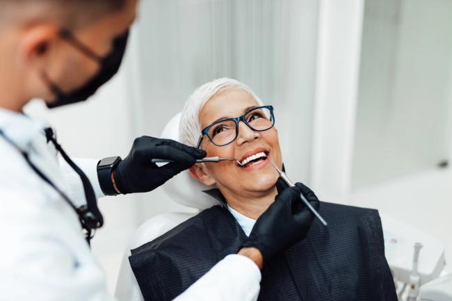 a woman is sitting in a dental chair while a dentist examines her teeth .