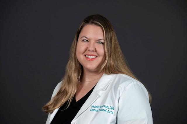 a woman in a white lab coat is smiling for the camera .