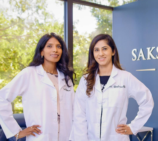 two female doctors stand in front of a saks dental studio sign