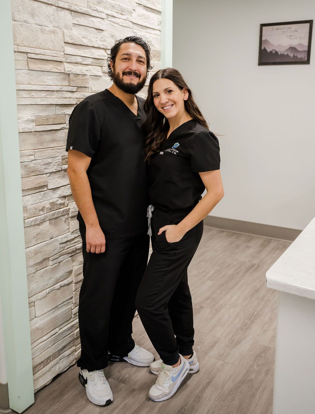 Eight smiling dental team members in black scrubs, some seated, some standing, in an office. One woman holds a sign that reads "TAKING SMILES TO NEW HEIGHTS".