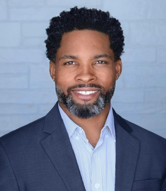 a man with a beard is wearing a suit and smiling for the camera .