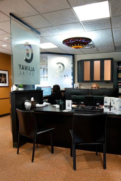 A modern dental office reception area with two staff members behind a black desk, and frosted glass partitions featuring the "Galaway Dental" logo.