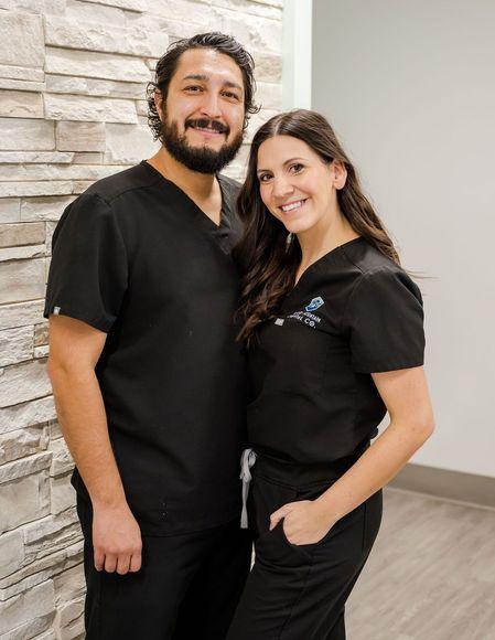 a man and a woman in scrubs are posing for a picture .