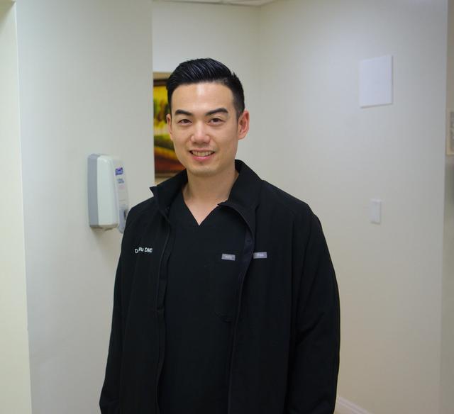a man in a black jacket is standing in a dental office .
