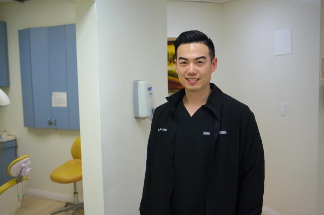 a man in a black jacket is standing in a dental office .