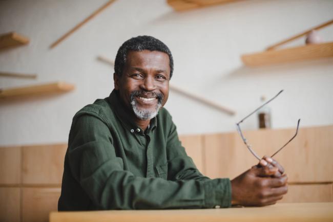 a man is sitting at a table holding glasses and smiling .