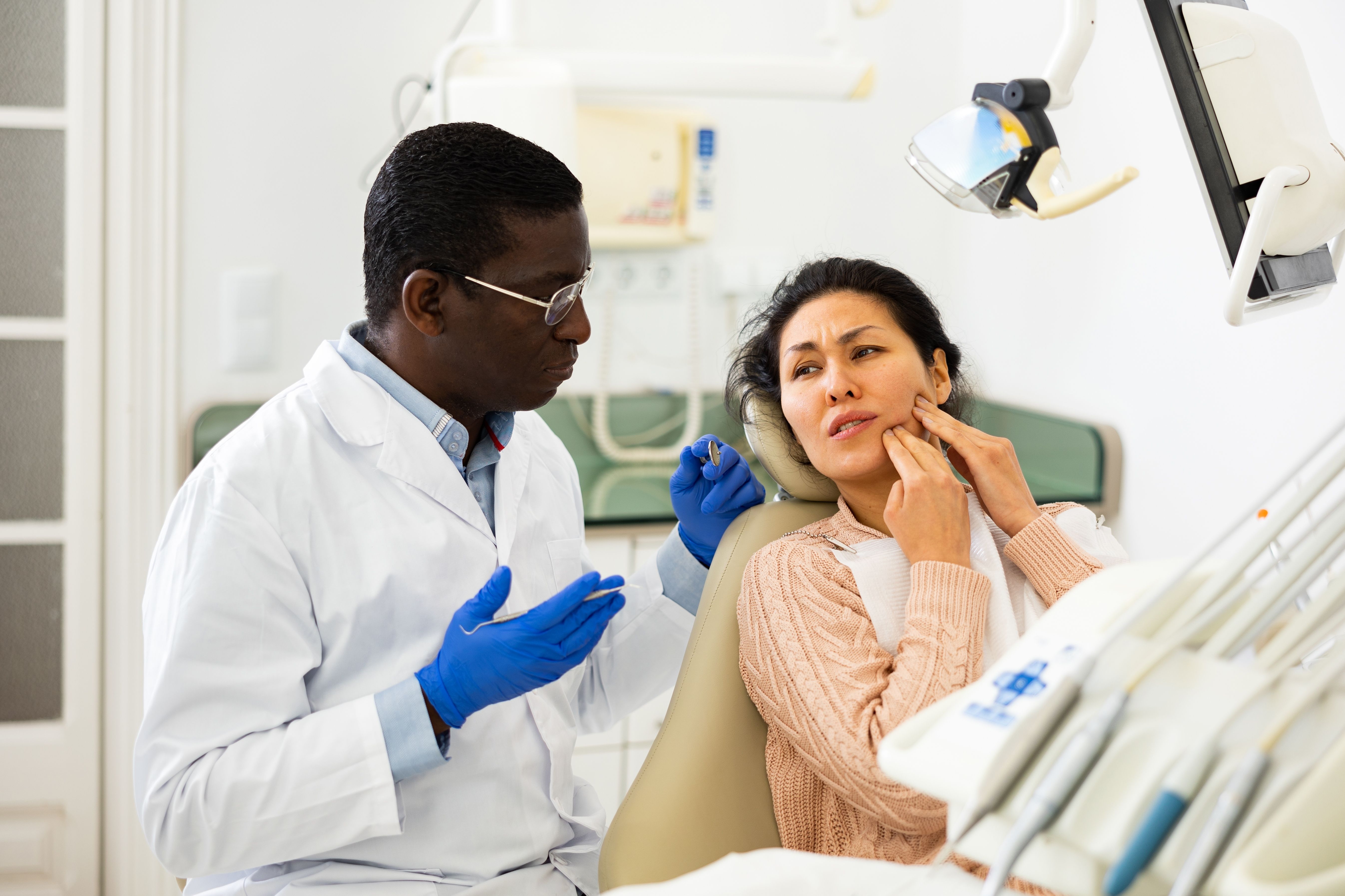 a dentist is talking to a patient in a dental chair .