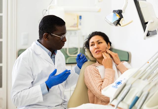 a dentist is talking to a patient in a dental chair .