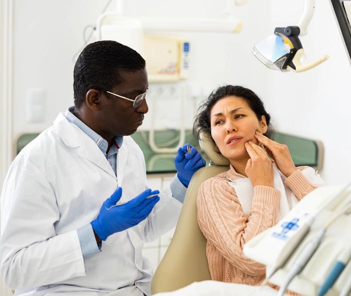 a dentist is talking to a patient in a dental chair .