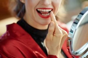 a woman is looking at her teeth in a mirror .