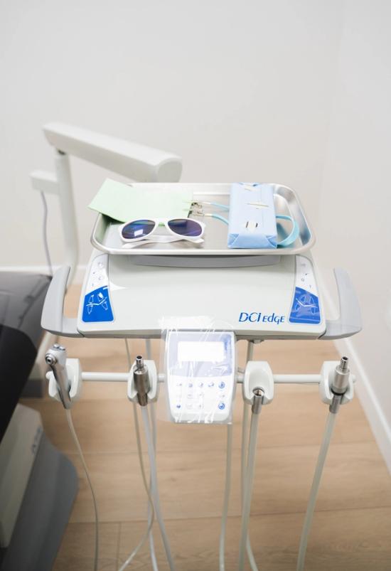 A DCI Edge dental delivery unit with a tray holding patient glasses and wrapped instruments.