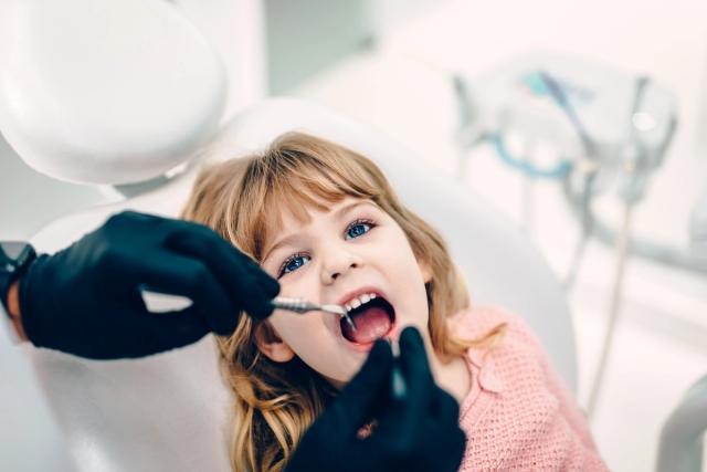 a little girl is getting her teeth examined by a dentist .