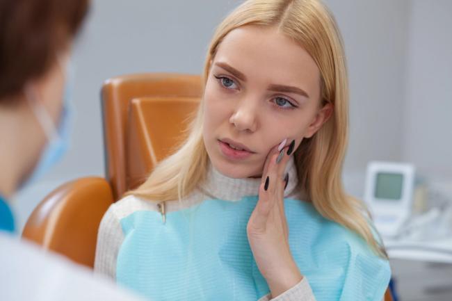 a woman is sitting in a dental chair with a toothache .