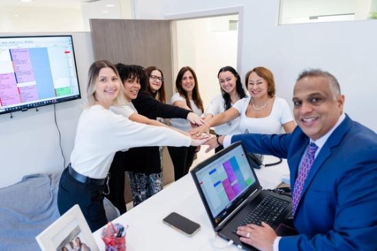 a group of people are putting their hands together in front of a laptop computer .
