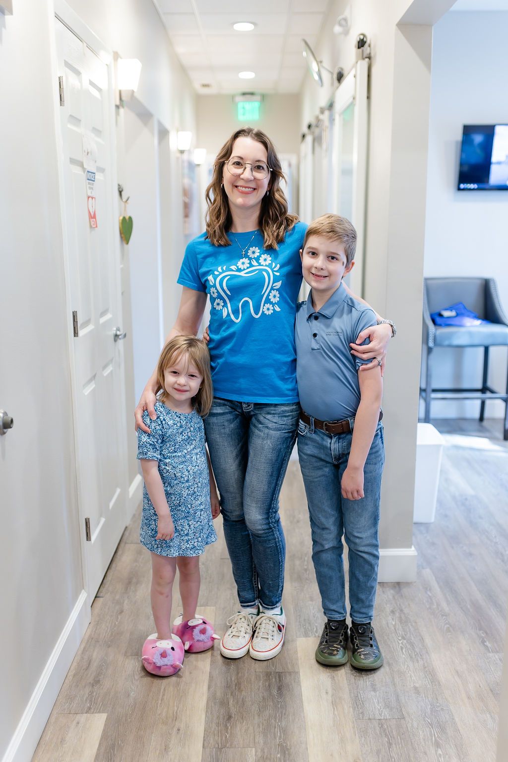 a woman in a blue shirt with a tooth on it poses with two children