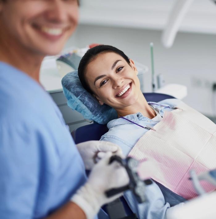 a woman is smiling while sitting in a dental chair .