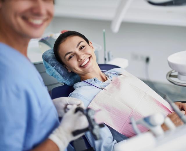 a woman is smiling while sitting in a dental chair .