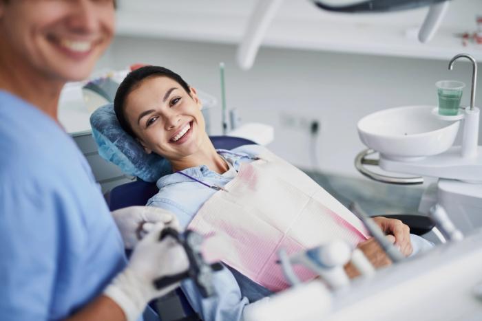 a woman is smiling while sitting in a dental chair .