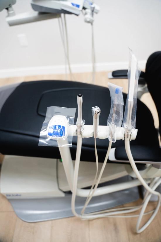 Dental chair with various instruments, some covered in clear plastic for hygiene.