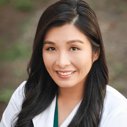 a woman in a white coat is smiling for the camera .