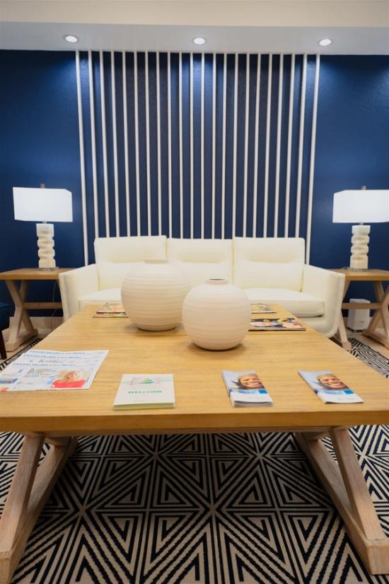 a waiting room with a wooden table and a white couch