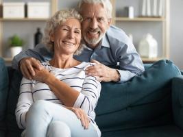 A smiling older couple embracing on a couch.