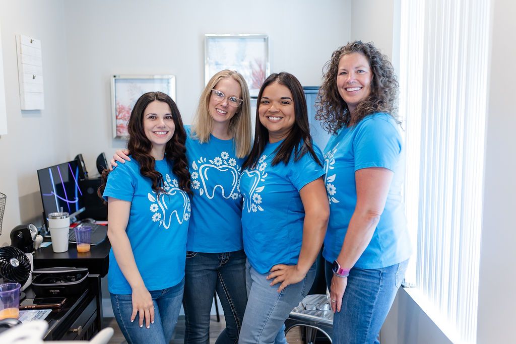 a group of women wearing blue shirts with a tooth on them are posing for a picture .