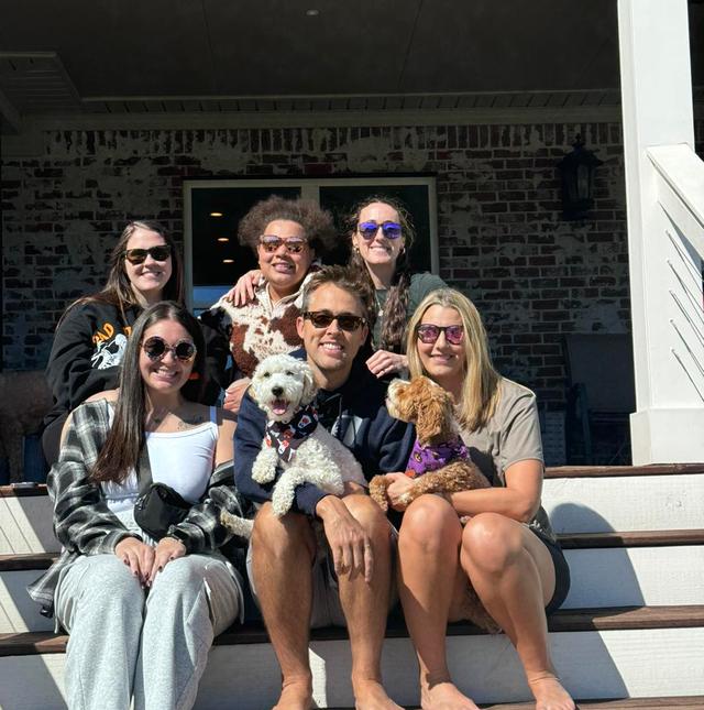 a group of people sitting on the steps of a house with their dogs