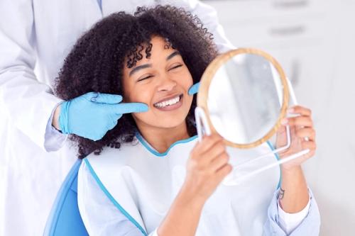 a woman is sitting in a dental chair looking at her teeth in a mirror .