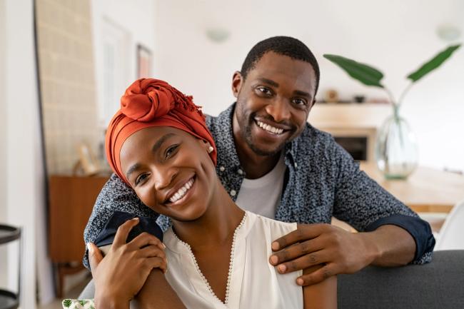 a man and a woman are smiling for the camera while sitting on a couch .
