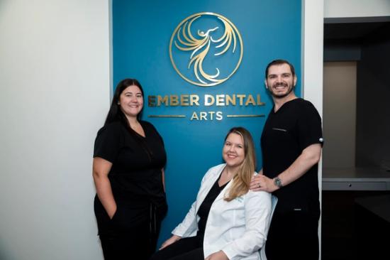 a group of dentists are posing for a picture in front of a sign .