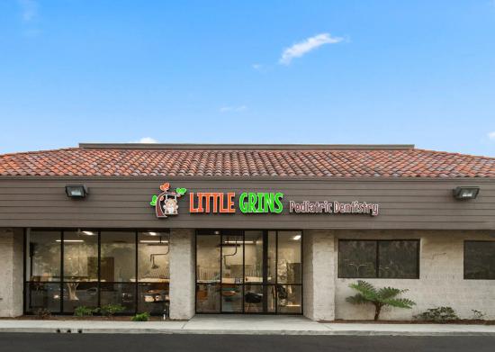 the front of a dental office with a sign that says little grins pediatric dentistry .