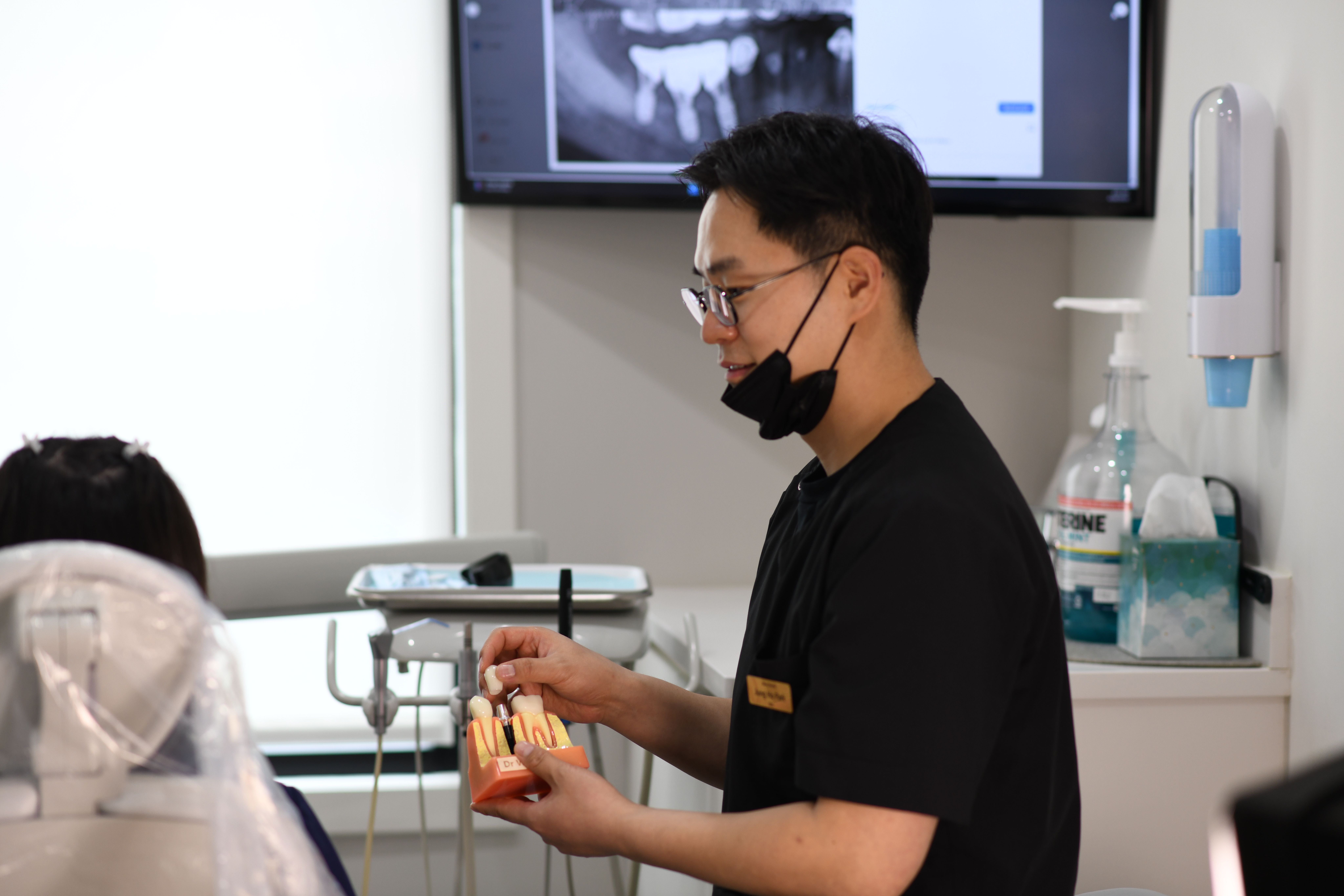 a dentist is holding a model of teeth in his hands in a dental office .