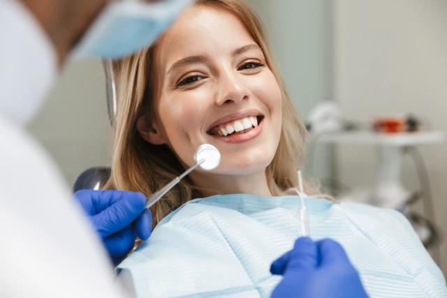 a woman is sitting in a dental chair while a dentist examines her teeth .