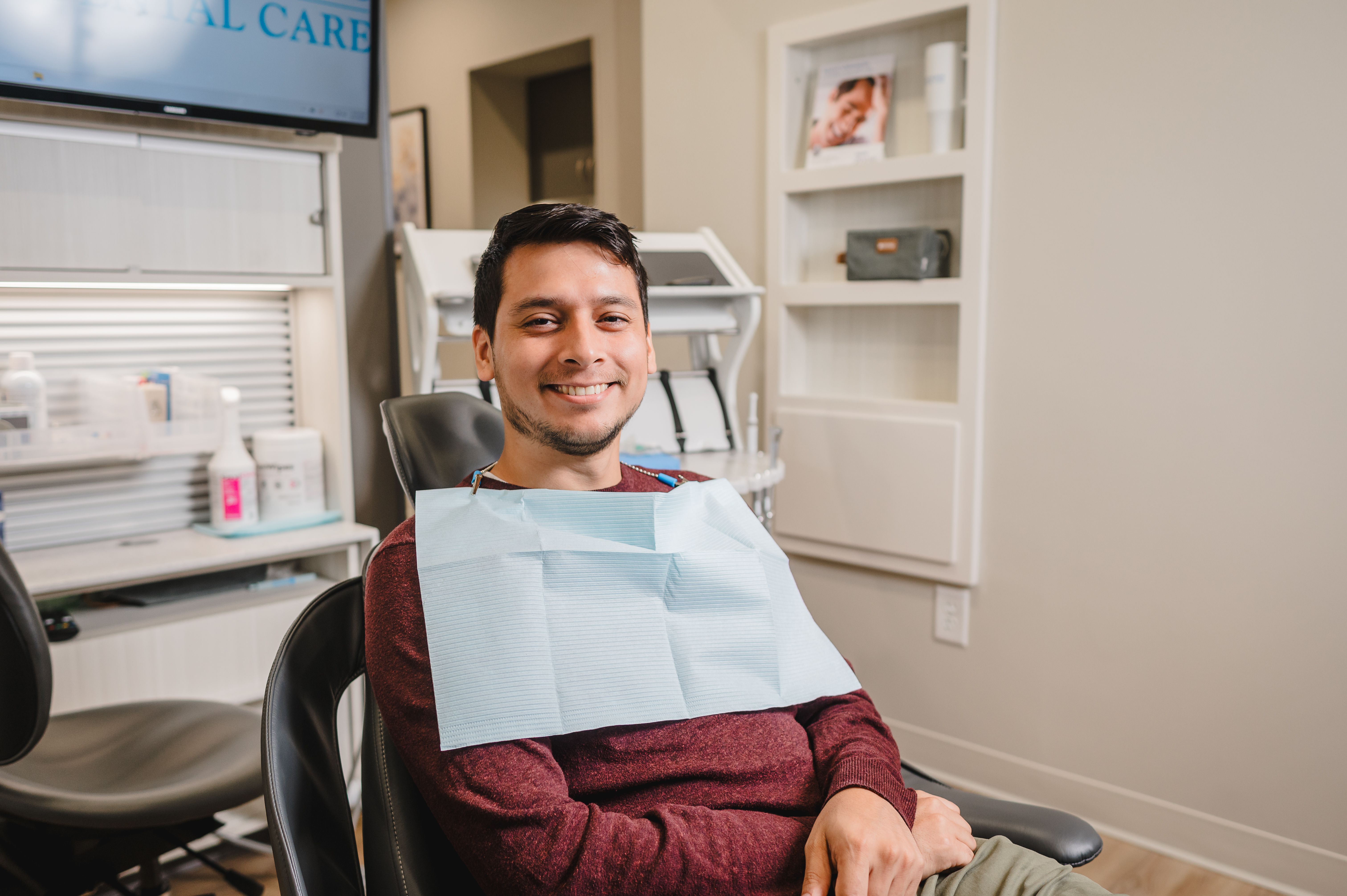 a man is sitting in a dental chair with a dental bib on his neck .