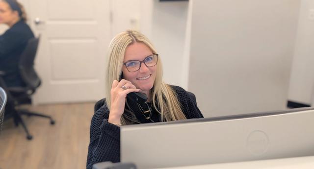 a woman is sitting in front of a computer talking on a cell phone .