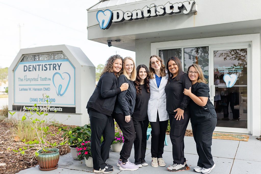 a group of women are posing for a picture in front of a dentistry office .